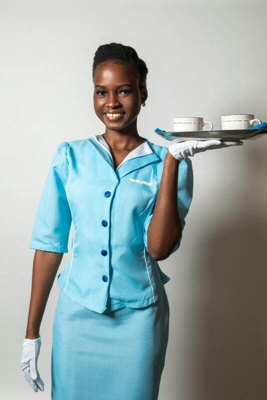 Portrait of a cheerful flight attendant in uniform offering service with a smile.