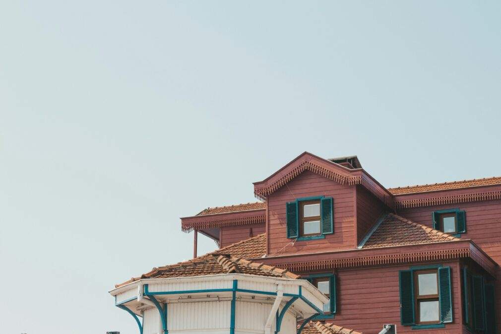 A captivating image of a traditional house featuring a unique roof design with wooden accents and vibrant shutters.