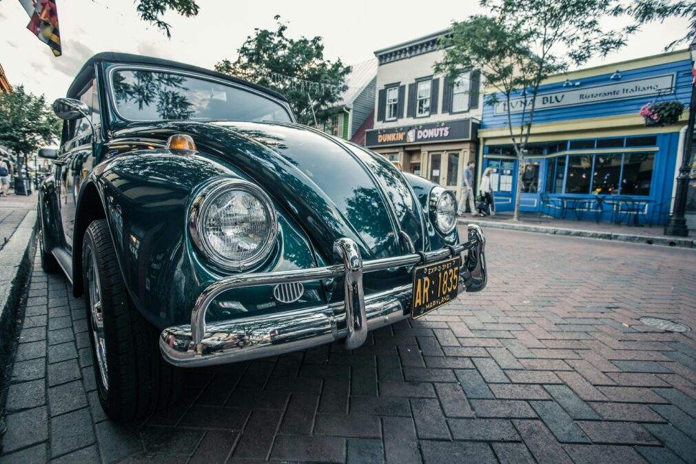 A classic green vintage car parked on a quaint brick street in Annapolis, Maryland.