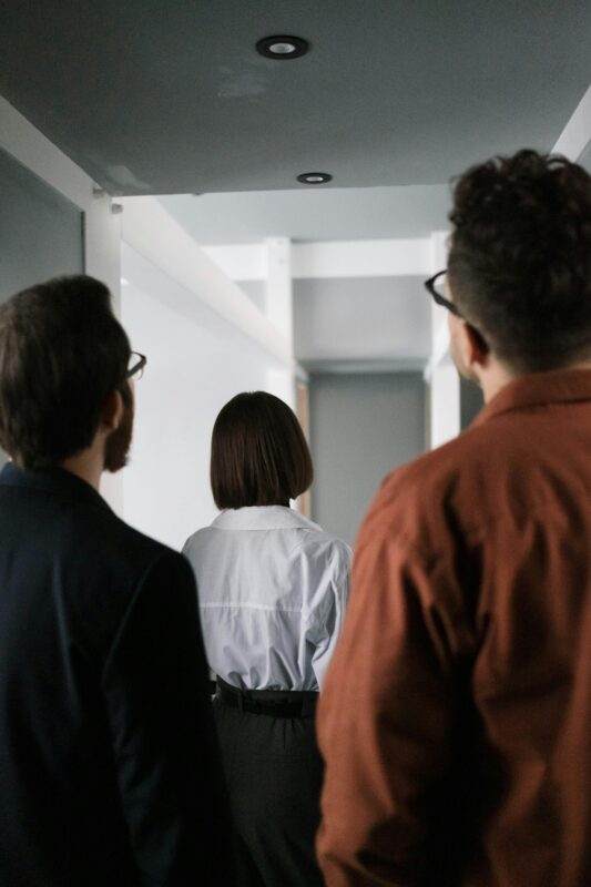 A businesswoman leading her team through a modern office corridor, showcasing teamwork and leadership.