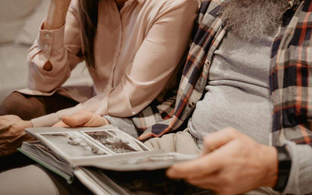 Senior couple sharing warm memories while looking through a family photo album indoors.