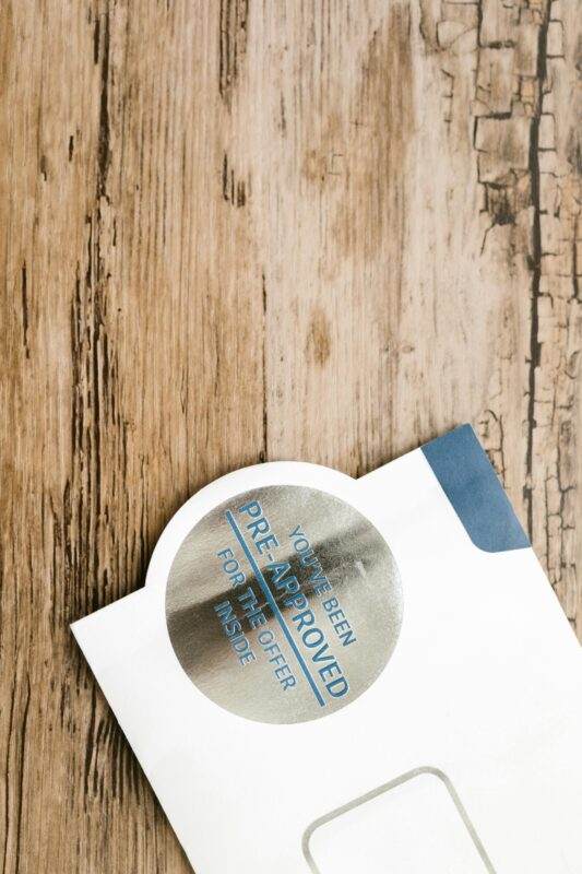 A pre-approved offer envelope with a sticker lies on a rustic wooden surface.