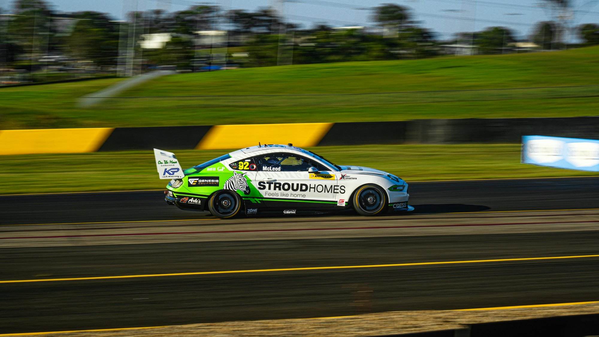 A sports car speeds down the racetrack at a vibrant outdoor setting.