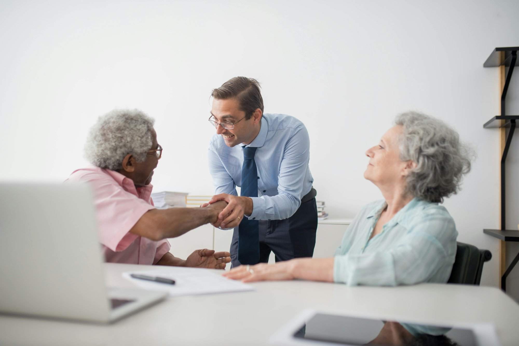 Business professional meeting with senior clients in an office setting, showcasing diversity and cooperation.