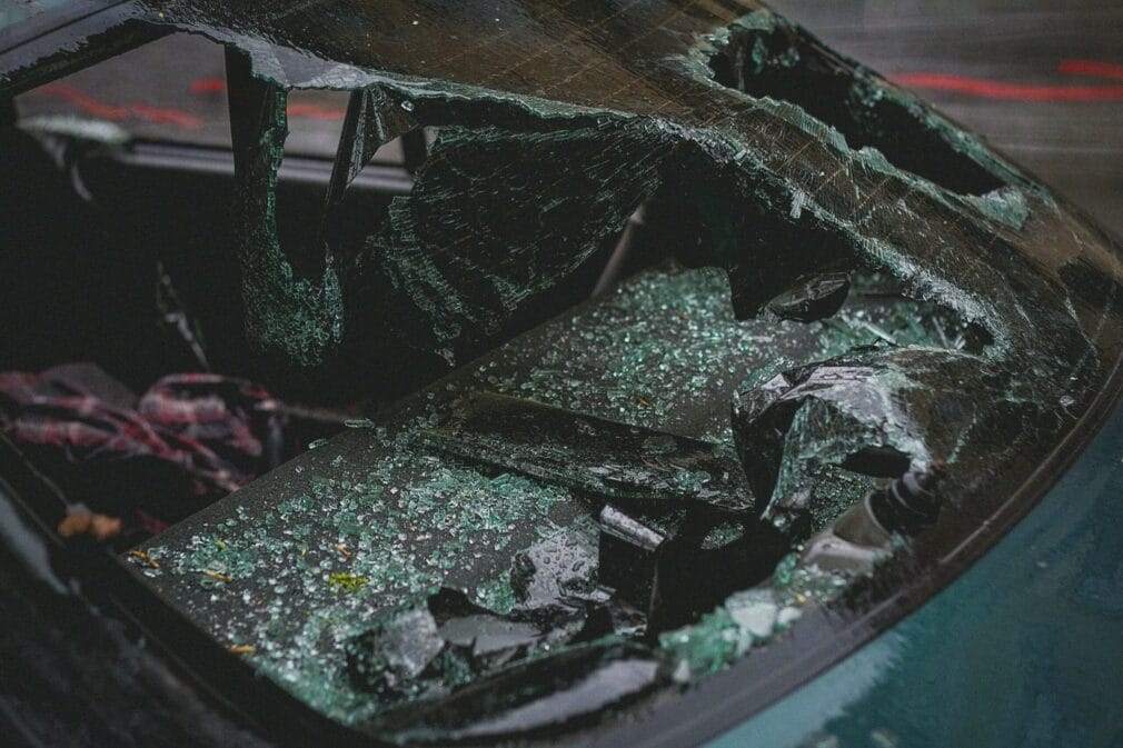 Detailed view of shattered car windshield after accident, emphasizing damage and broken glass.