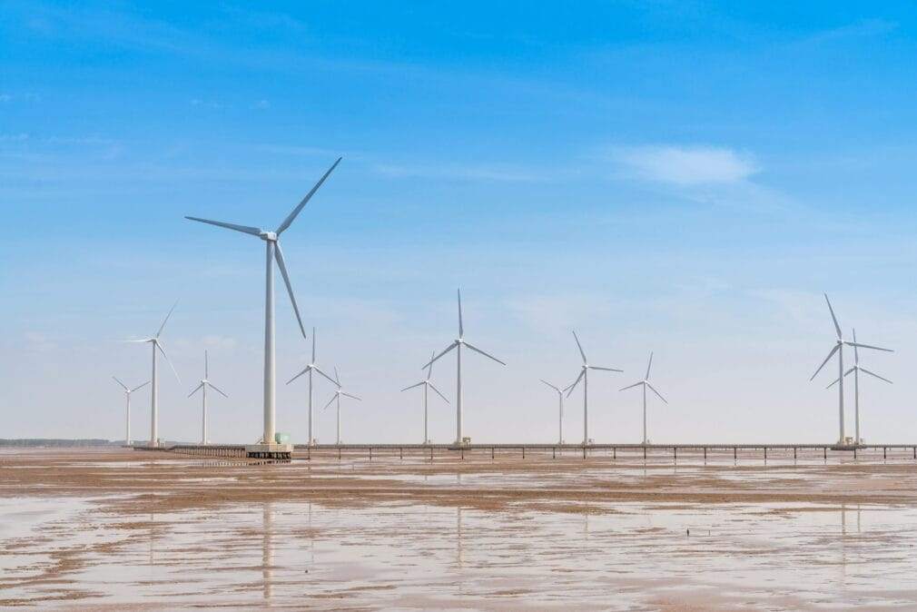 Expansive wind farm with turbines under a bright blue sky, showcasing renewable energy.
