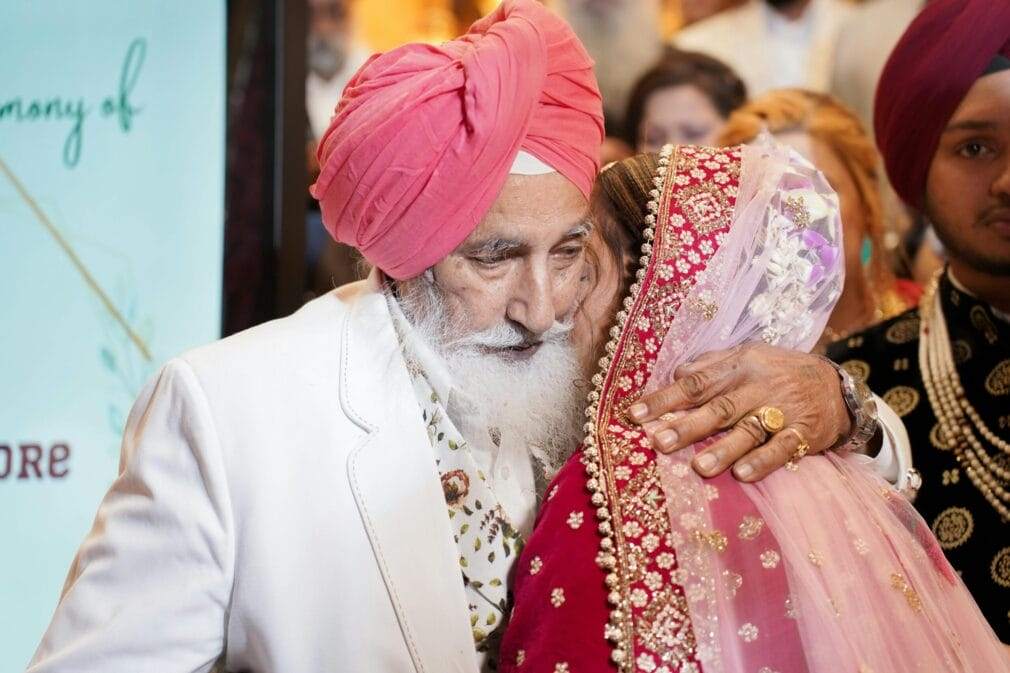 A heartfelt embrace between an elderly man and a bride during a traditional wedding ceremony.