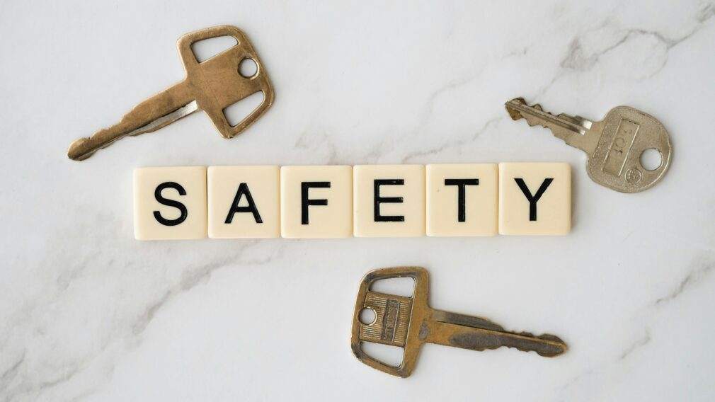 Close-up image of keys and scrabble tiles spelling 'safety' on a marble surface.