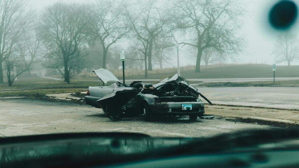 A foggy morning with a severely damaged car on a deserted street in Chicago.