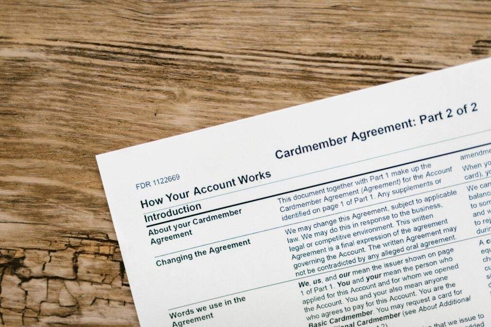 Close-up of a credit card agreement document on a textured wooden desk.