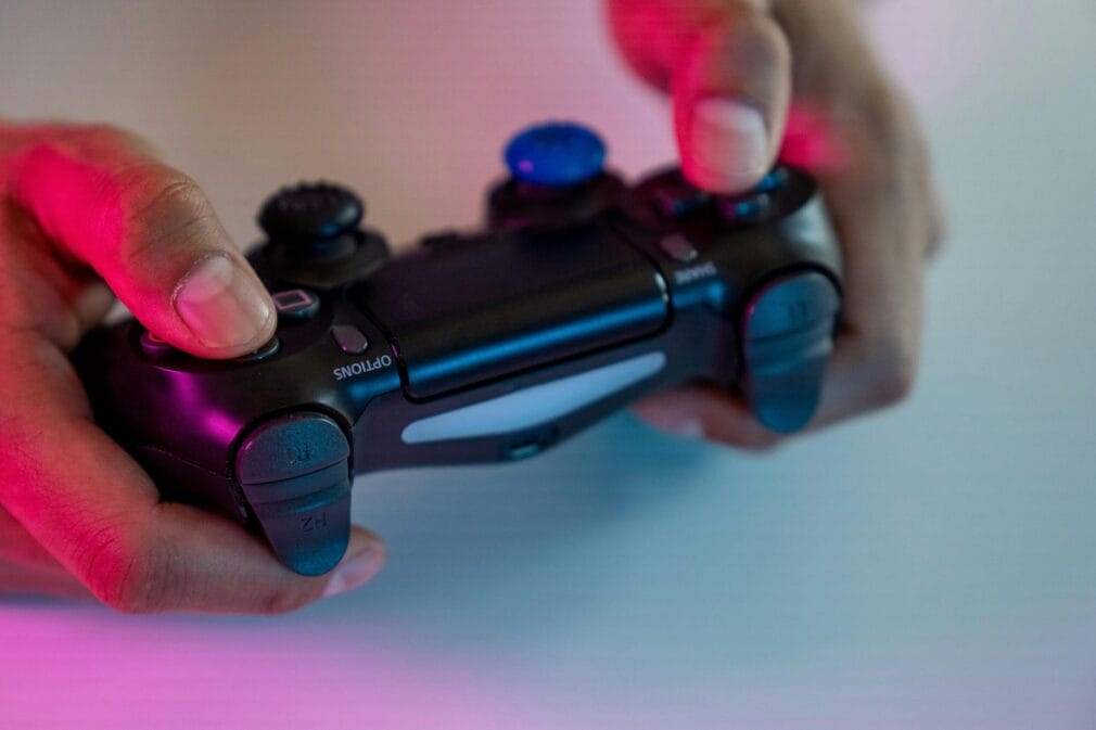 A tight shot of hands gripping a video game controller with colorful lighting.